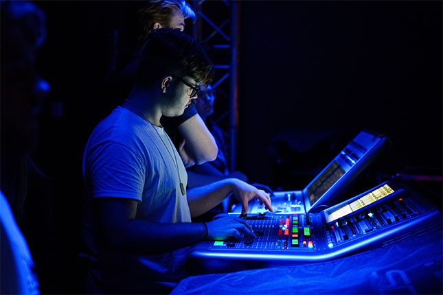 Young student pushing buttons and moving sliders on a music deck