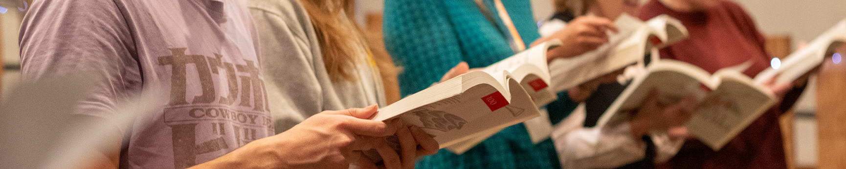 Staff and student choir singing carols at rehearsals, holding carol books.